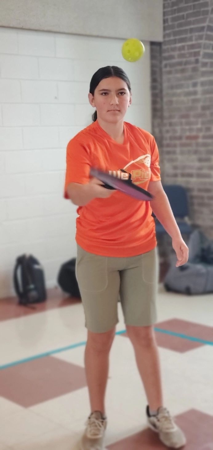 Girl playing pickleball indoors with paddle