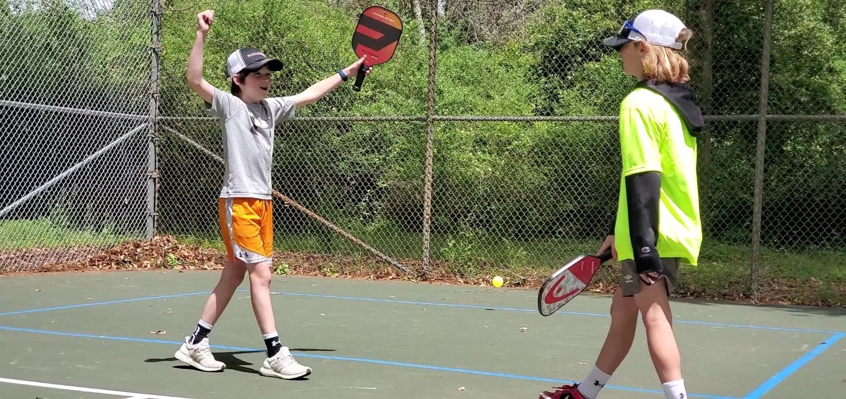 Kids playing pickleball on outdoor court