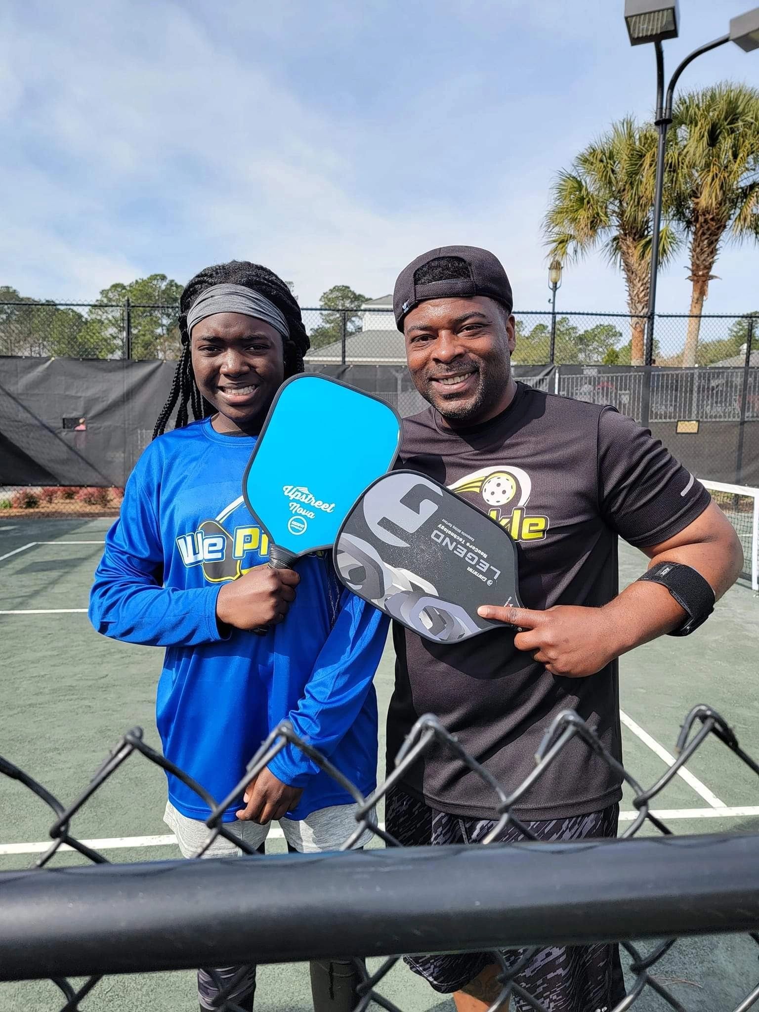 Two players holding pickleball paddles on court
