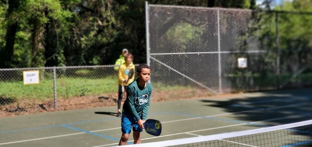Young boy playing pickleball outdoors