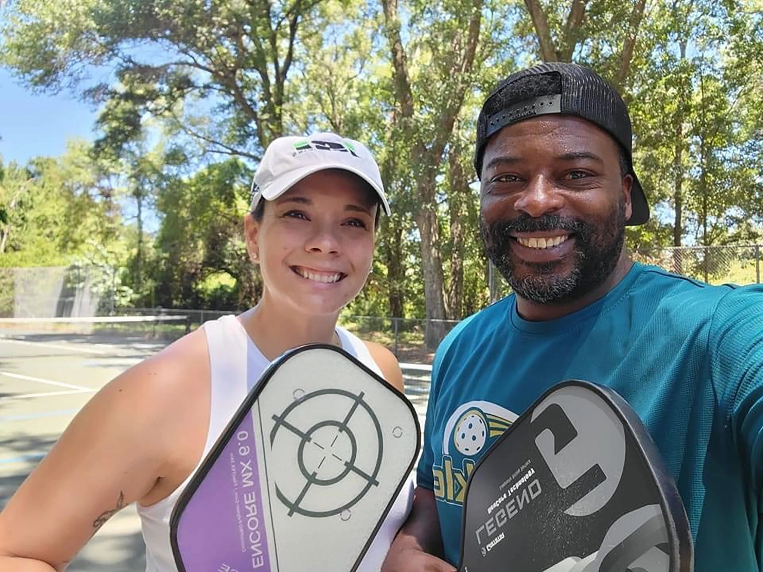 Two people holding pickleball paddles outdoors